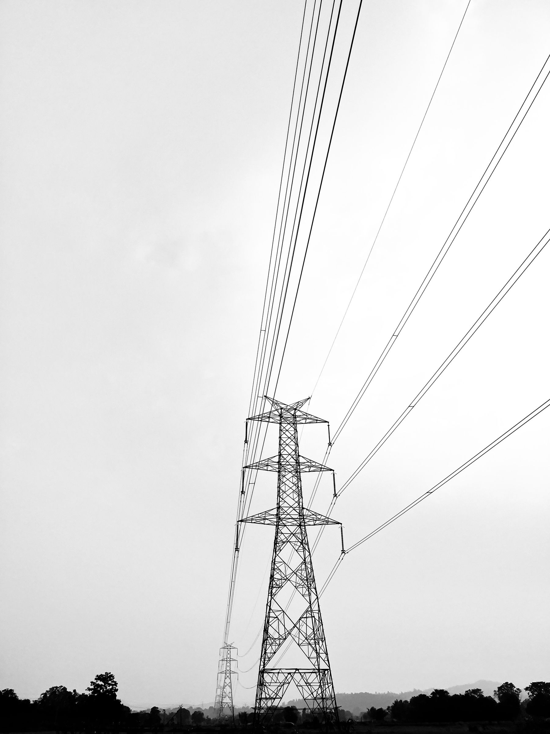 Black and white transmission towers and power lines reaching into the sky.